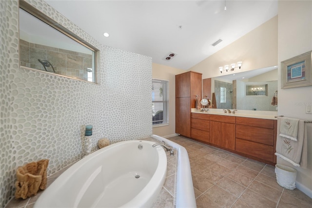 bathroom with tile floors, a relaxing tiled bath, vaulted ceiling, and vanity