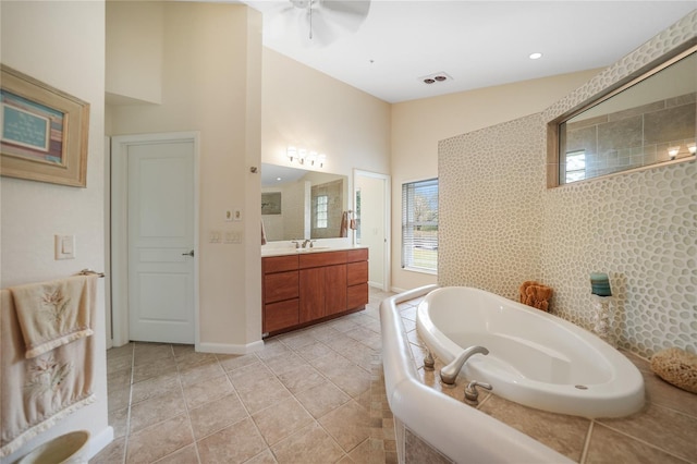 bathroom with tiled tub, tile floors, ceiling fan, and large vanity