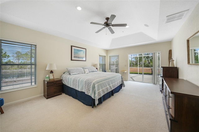 bedroom with access to exterior, light colored carpet, ceiling fan, and a tray ceiling