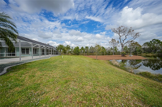 view of yard with a water view, a patio, and glass enclosure