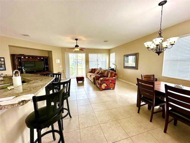 dining room with light tile patterned floors, ceiling fan with notable chandelier, a textured ceiling, and sink