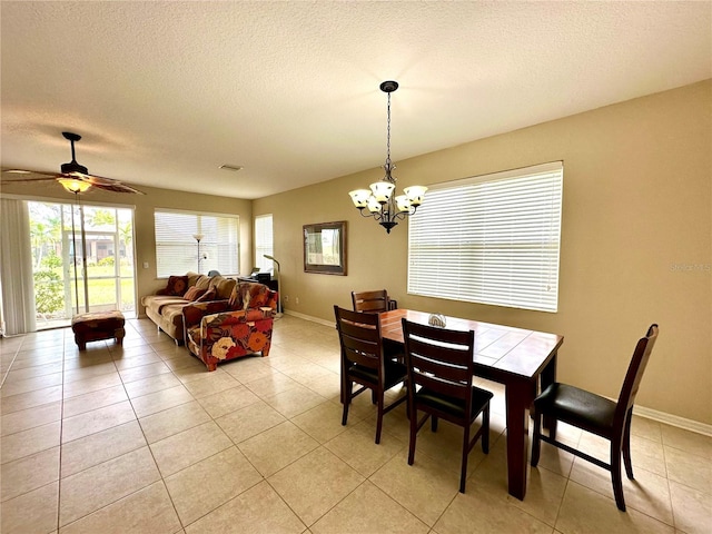 dining area with a textured ceiling, light tile patterned floors, and ceiling fan with notable chandelier