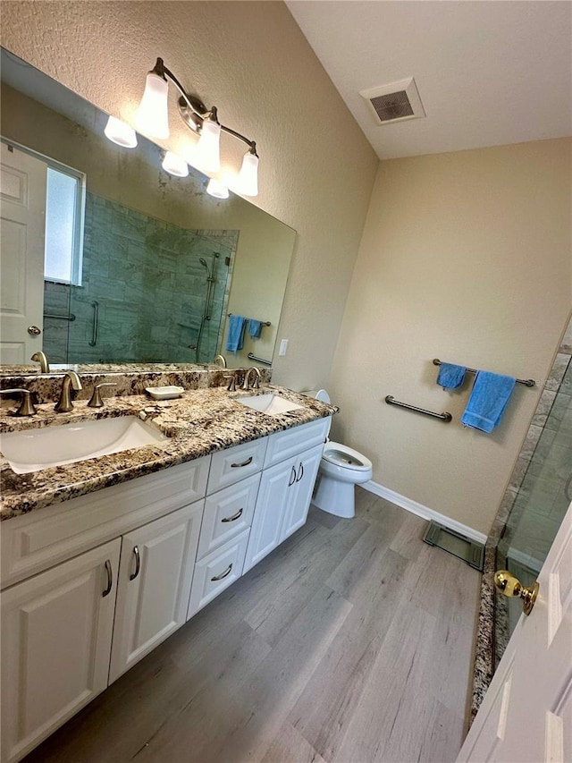 bathroom featuring hardwood / wood-style floors, vanity, toilet, and walk in shower