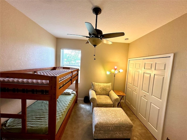 bedroom with ceiling fan, a closet, dark carpet, and a textured ceiling