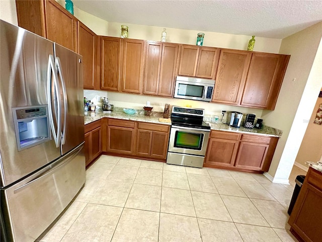 kitchen featuring a textured ceiling, light tile patterned floors, and stainless steel appliances