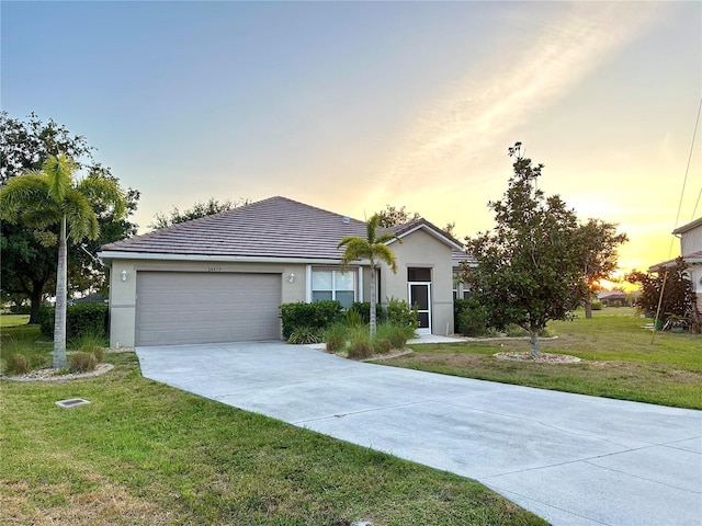 ranch-style home featuring a lawn and a garage