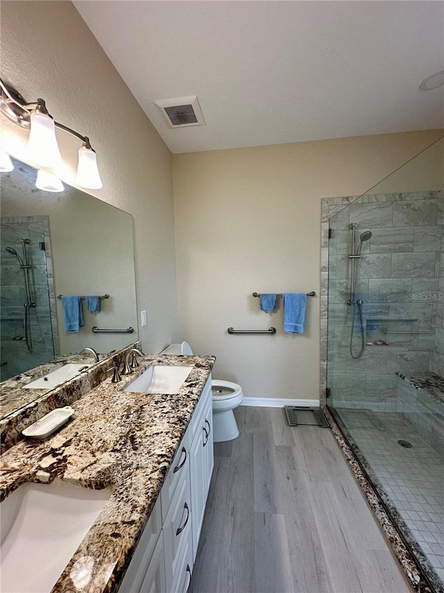 bathroom featuring tiled shower, wood-type flooring, vanity, and toilet