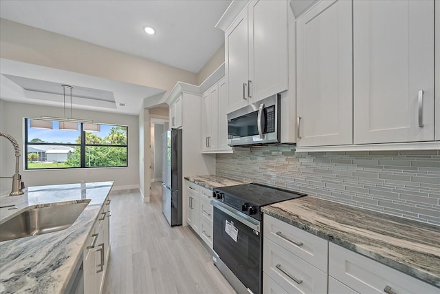 kitchen featuring light wood-type flooring, white cabinets, stainless steel appliances, and decorative backsplash