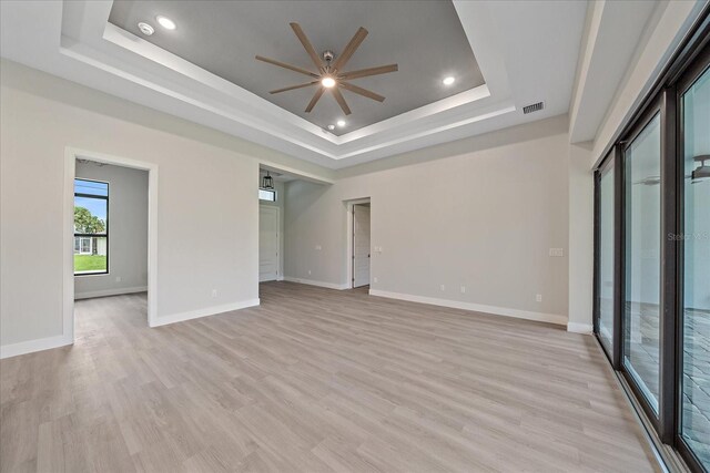 unfurnished room featuring light hardwood / wood-style flooring, ceiling fan, and a tray ceiling