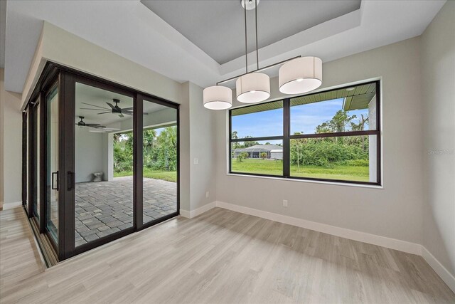 spare room with a tray ceiling, ceiling fan, and light hardwood / wood-style floors