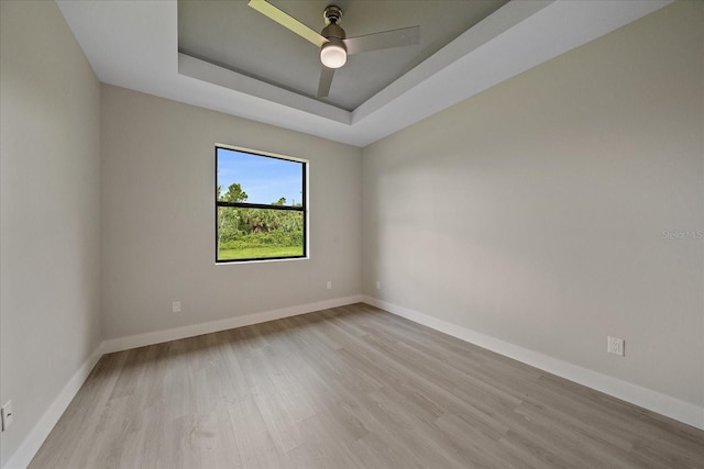 spare room with ceiling fan, a raised ceiling, and light hardwood / wood-style flooring