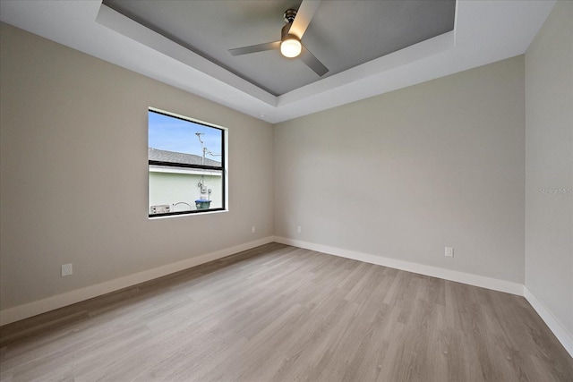 unfurnished room featuring a tray ceiling, ceiling fan, and light hardwood / wood-style flooring