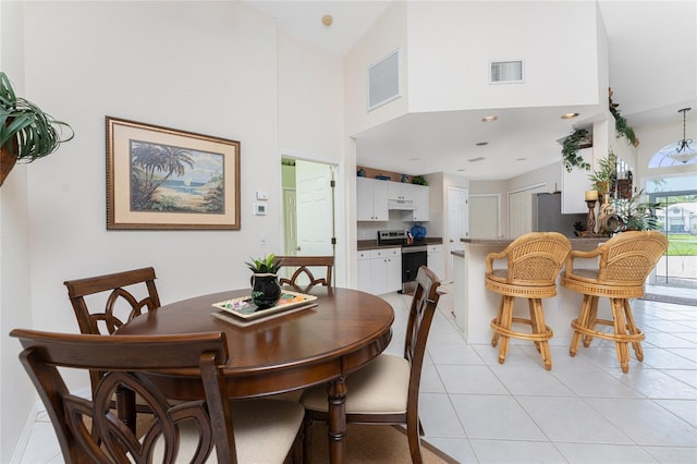 dining room featuring high vaulted ceiling and light tile floors