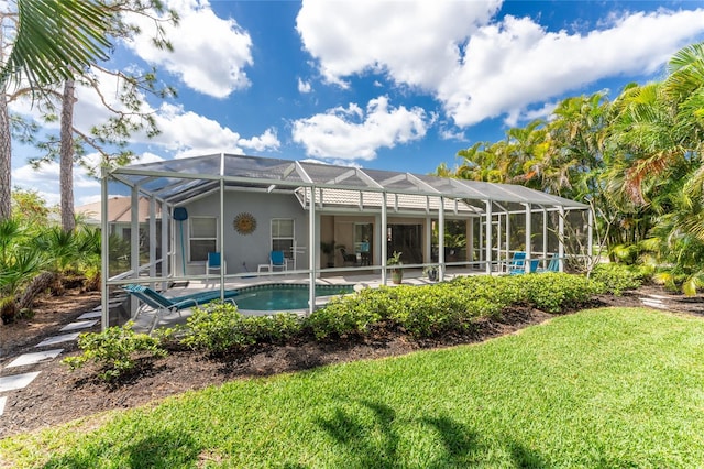 back of house featuring a lawn, a patio, and a lanai