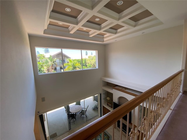 stairway featuring a high ceiling, beam ceiling, and coffered ceiling