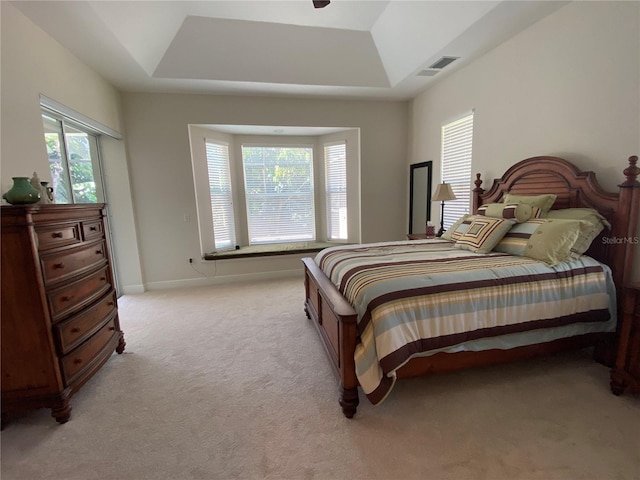 carpeted bedroom featuring ceiling fan and a raised ceiling