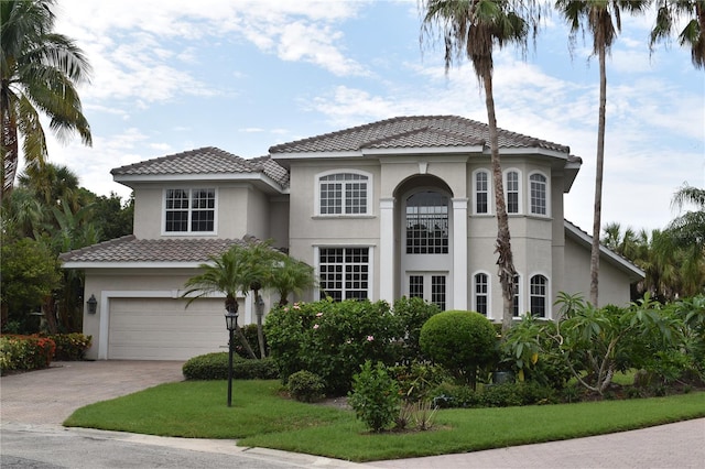 mediterranean / spanish home featuring a front yard and a garage