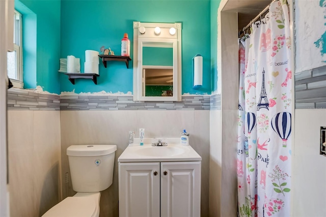 bathroom featuring toilet, tasteful backsplash, vanity, and tile walls