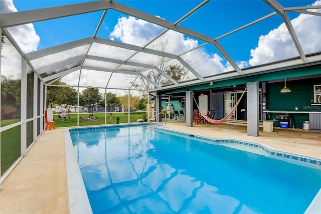 view of pool with a lawn, a patio area, and a lanai