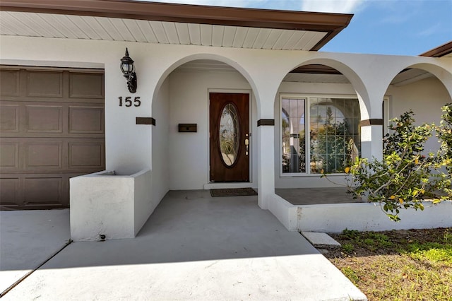 view of exterior entry with covered porch and a garage