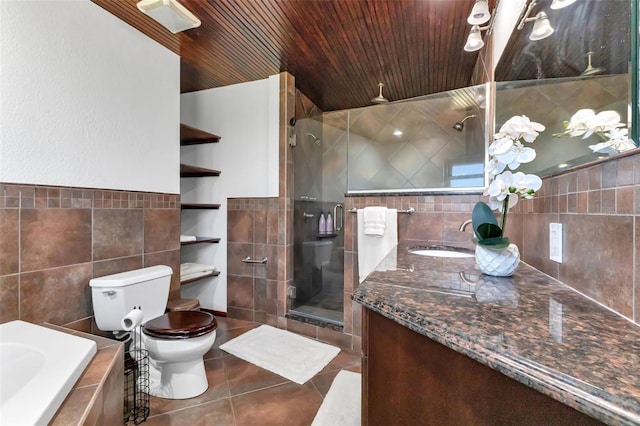 bathroom featuring tile walls, toilet, a shower with shower door, tile floors, and vanity