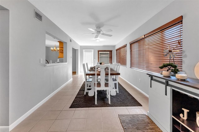 tiled dining room featuring ceiling fan with notable chandelier