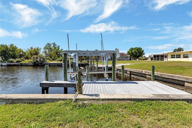 view of dock with a lawn and a water view