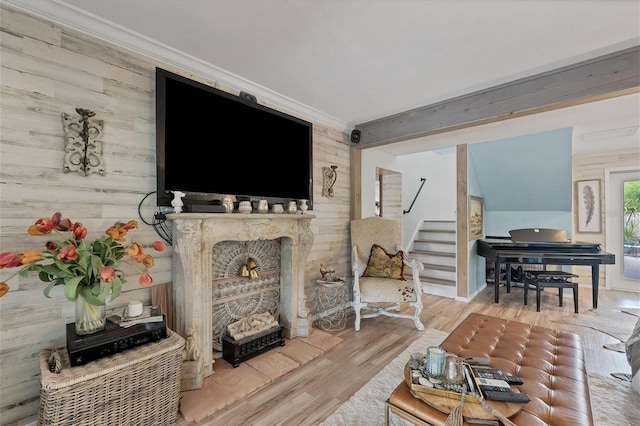 living room featuring wooden walls, crown molding, light hardwood / wood-style floors, and a fireplace