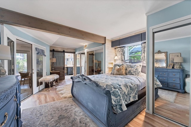 bedroom with a barn door, multiple windows, and light wood-type flooring