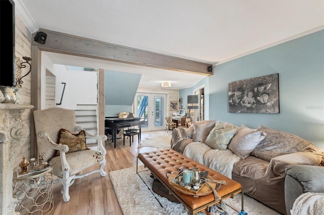 living room featuring beamed ceiling, french doors, ornamental molding, and light wood-type flooring