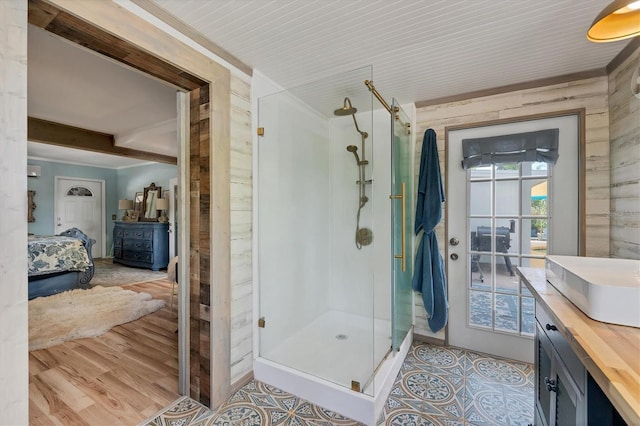 bathroom with tile floors, wood walls, walk in shower, and vanity