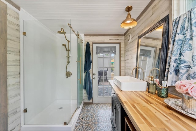 bathroom with walk in shower, tile floors, vanity, and wood walls