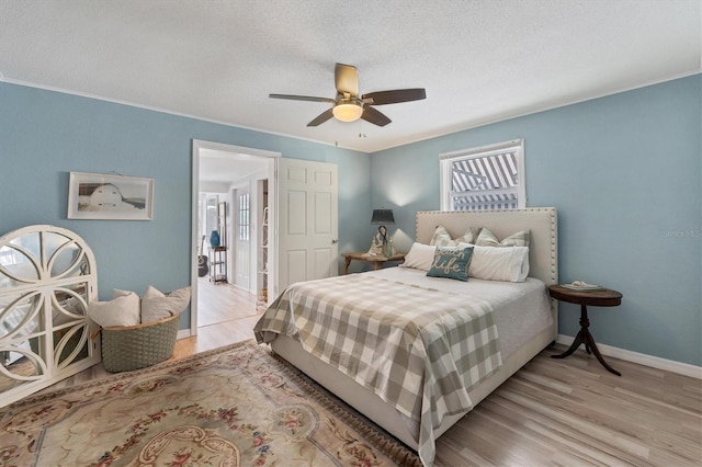 bedroom with a textured ceiling, ceiling fan, and light wood-type flooring