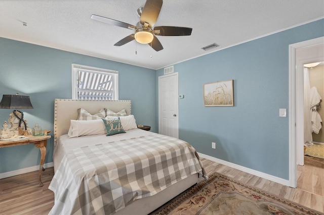 bedroom with light hardwood / wood-style floors, a textured ceiling, and ceiling fan