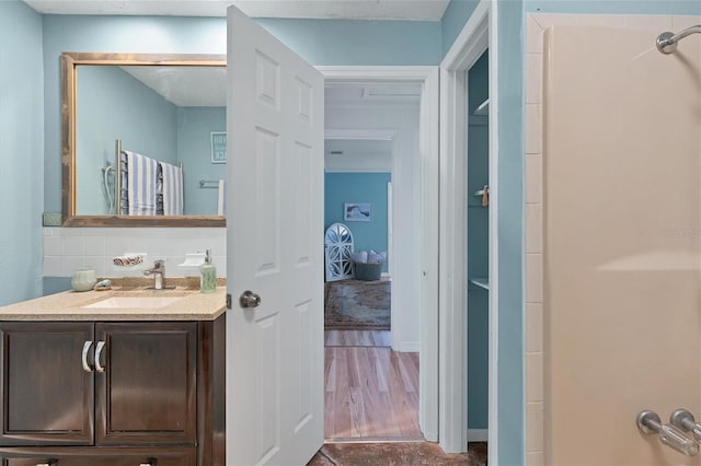 bathroom with wood-type flooring, tasteful backsplash, and oversized vanity