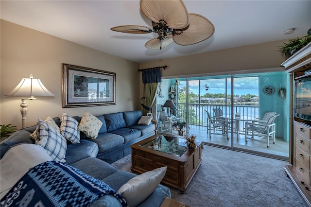 carpeted living room featuring ceiling fan and a water view