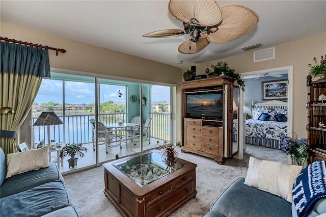 living room featuring light colored carpet, ceiling fan, and a water view