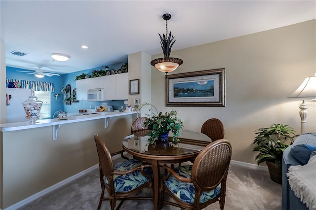 carpeted dining area with ceiling fan