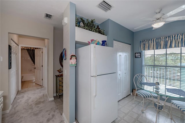 kitchen featuring white refrigerator, ceiling fan, and light carpet