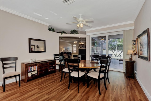 dining room featuring ornamental molding, ceiling fan with notable chandelier, and dark hardwood / wood-style floors