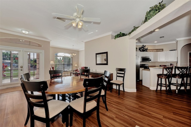 dining space featuring ceiling fan with notable chandelier, french doors, dark wood-type flooring, and crown molding