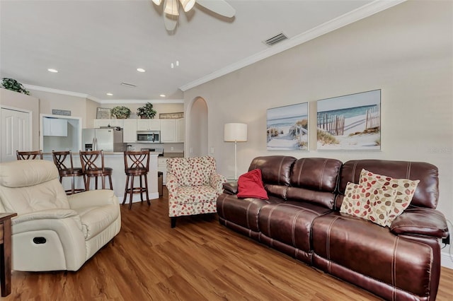 living room with ornamental molding, ceiling fan, and light wood-type flooring