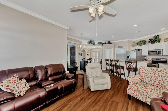 living room with ceiling fan with notable chandelier, ornamental molding, and light wood-type flooring