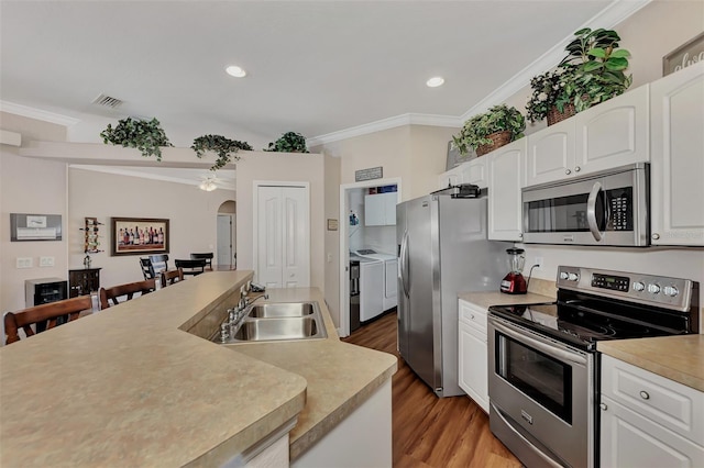 kitchen with washer and clothes dryer, white cabinets, sink, stainless steel appliances, and light hardwood / wood-style flooring