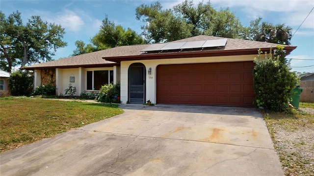 single story home with solar panels, a front lawn, and a garage