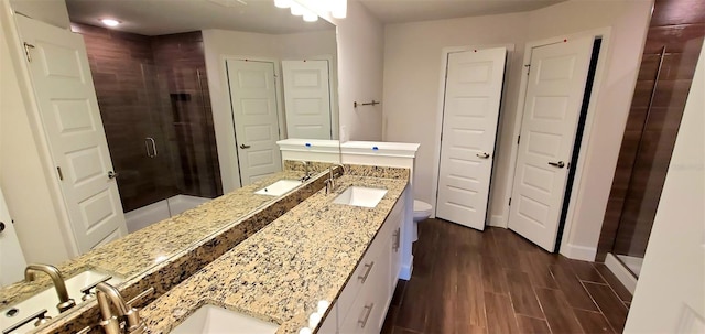 bathroom with hardwood / wood-style flooring, vanity, toilet, and a shower with shower door