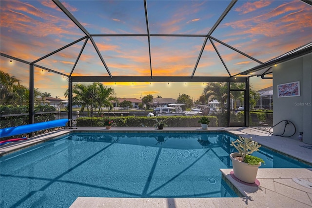 pool at dusk with a patio area and a lanai