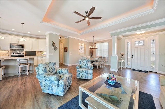 living room featuring dark wood-type flooring, ornate columns, crown molding, and ceiling fan