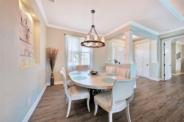 dining area with ornamental molding, dark wood-type flooring, an inviting chandelier, and ornate columns