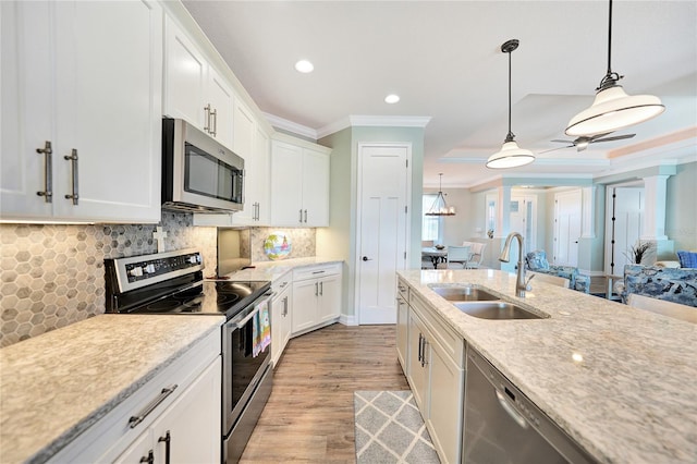 kitchen featuring hanging light fixtures, white cabinetry, sink, light hardwood / wood-style flooring, and stainless steel appliances